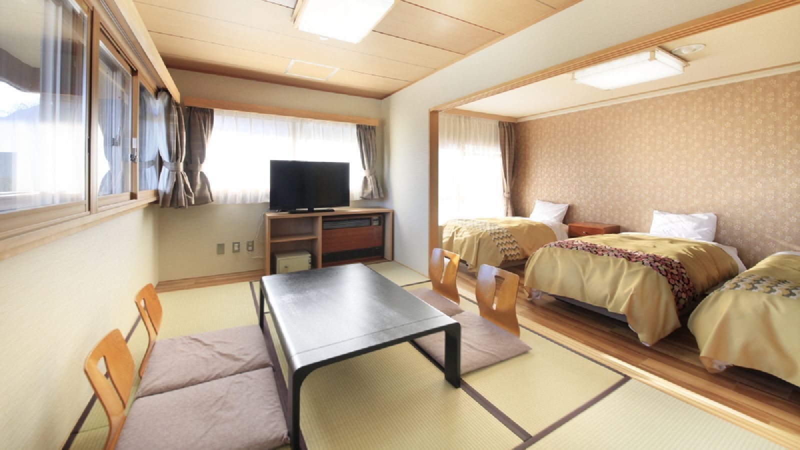 Habitació amb dos llits, televisió, taula i cadires.