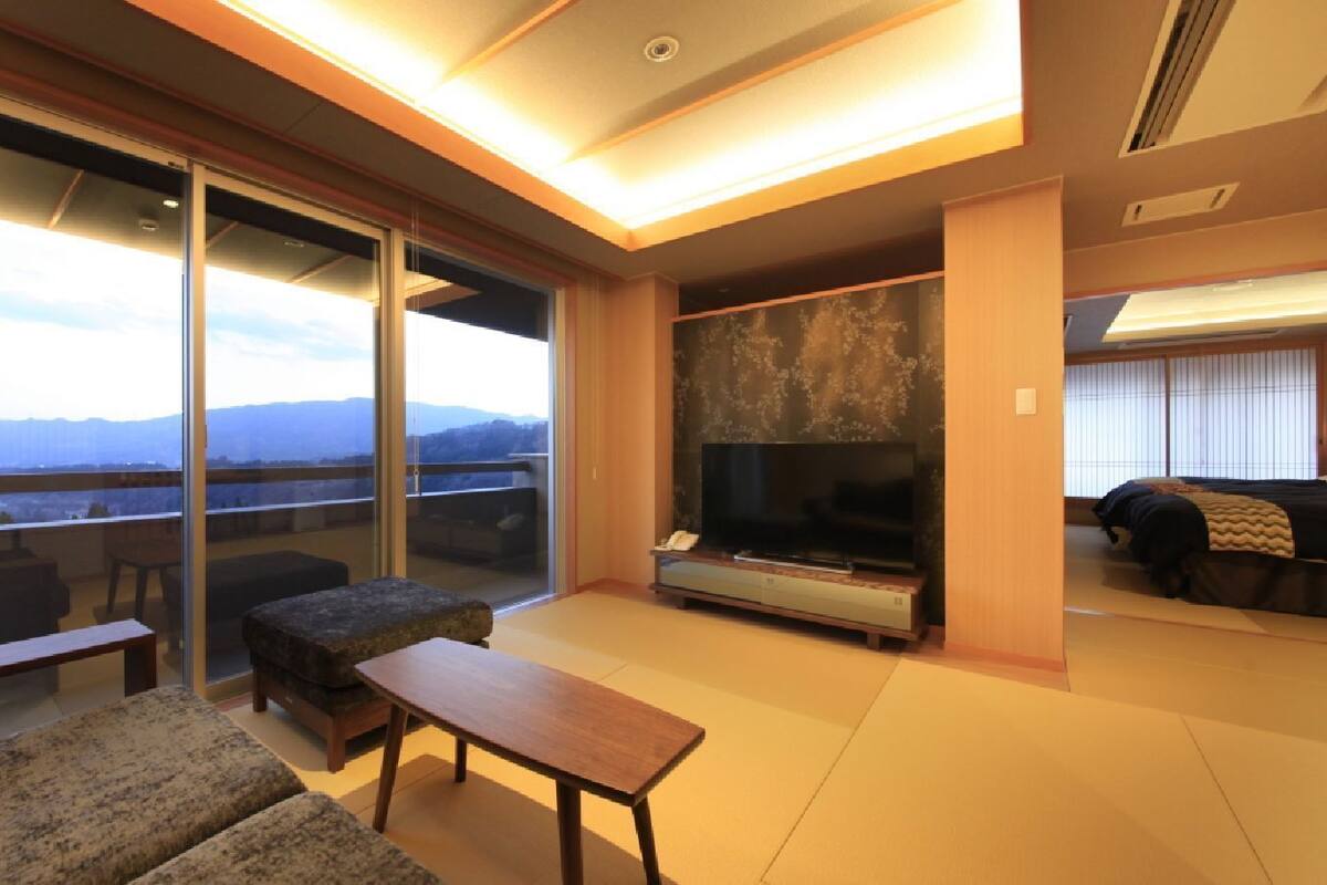 A modern living room with a large TV, sliding glass doors to a balcony, and a sofa.