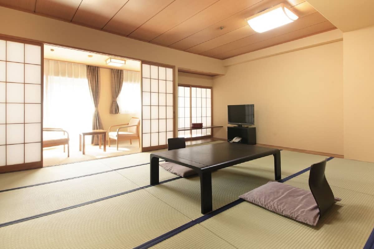 A tatami mat room with a low table, a television, and sliding doors.