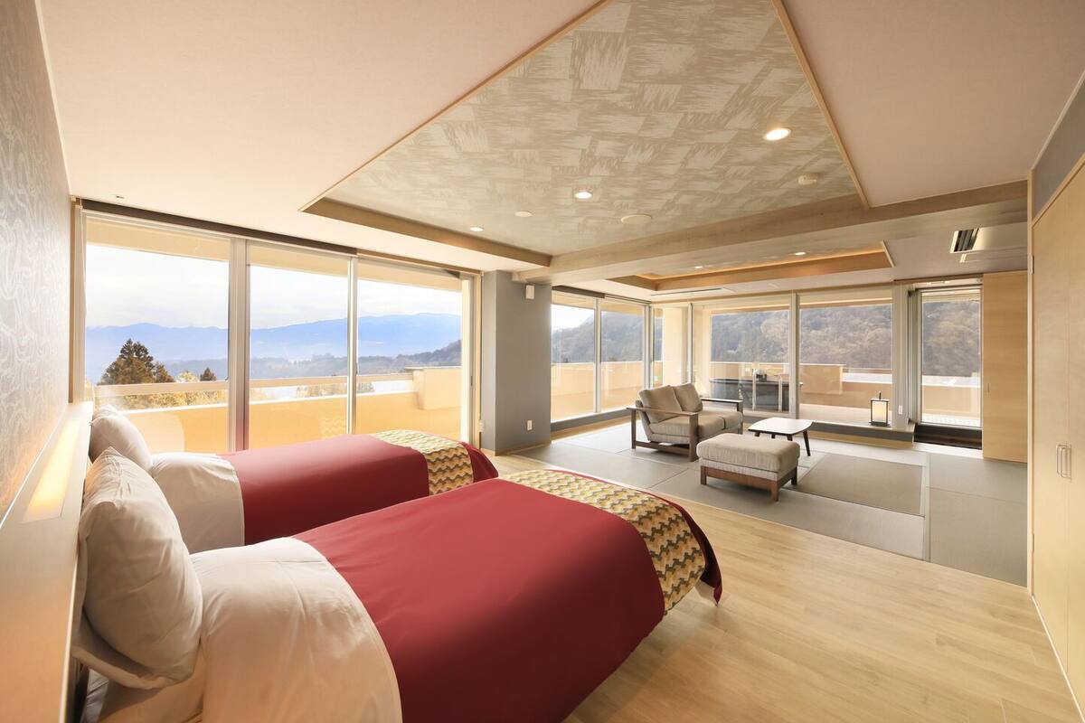 A modern hotel room with a large bed, a seating area, and a balcony with a view.