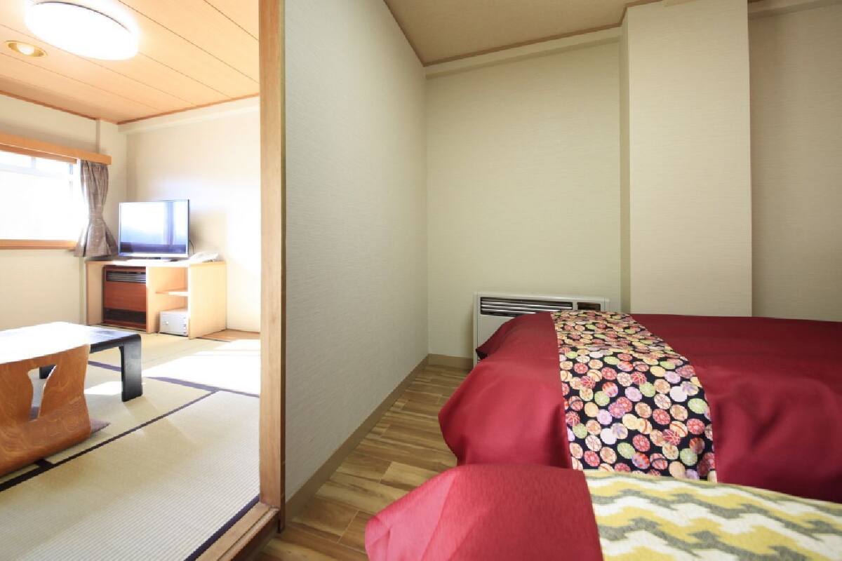 A compact room with a bed, a small table, and a television.