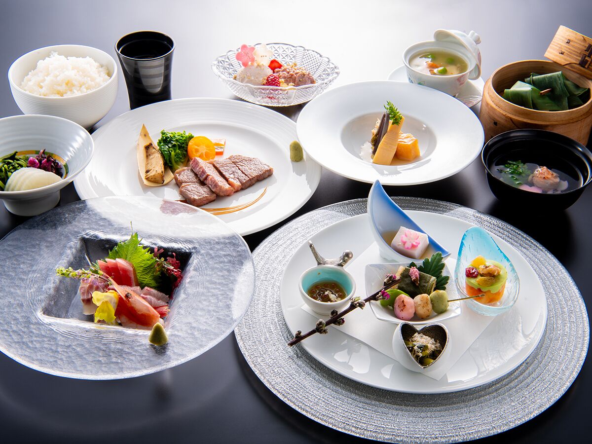 A variety of dishes on a table, including sushi, sashimi, and other Asian cuisine.