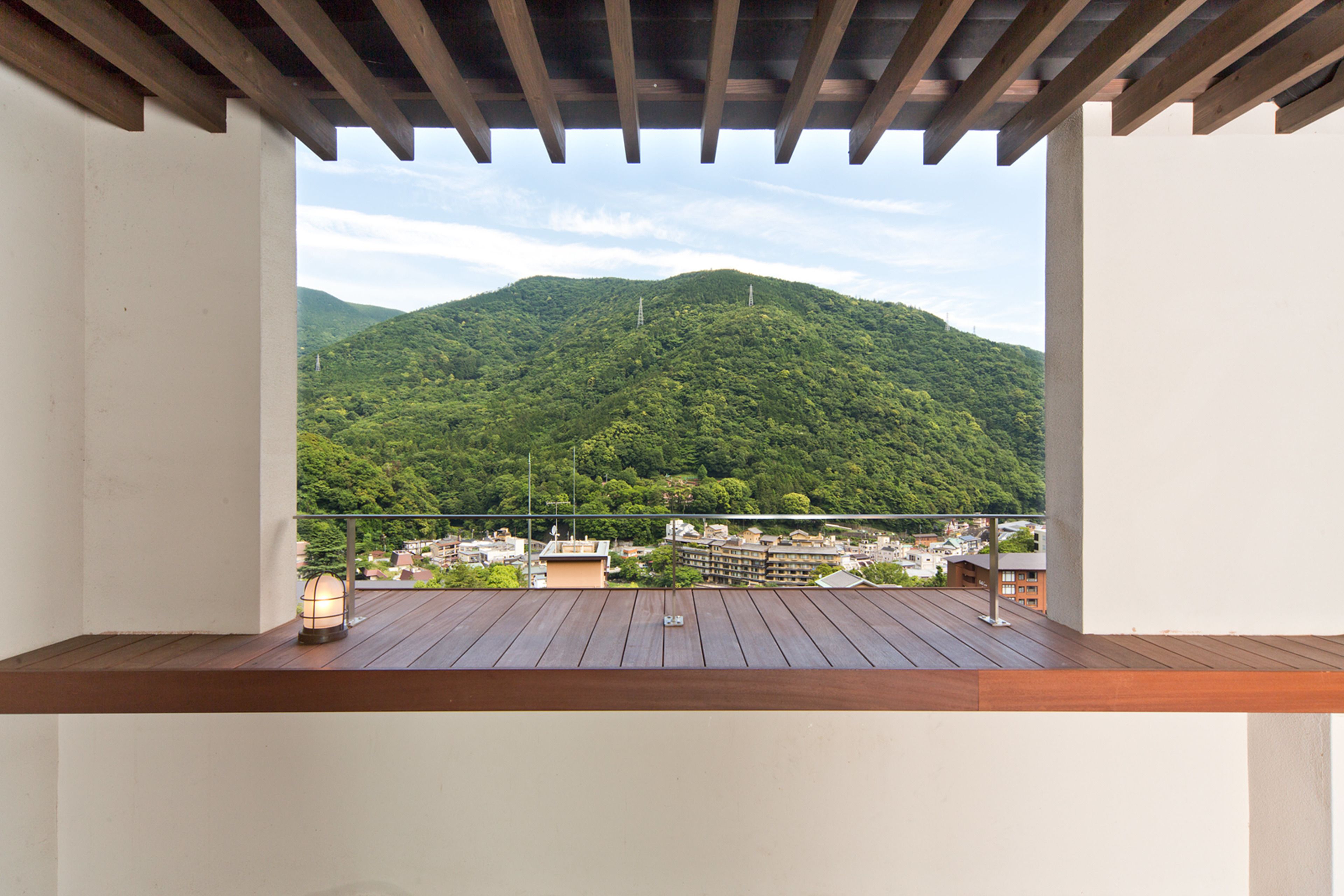 A wooden deck with a view of a green mountain and buildings in the distance.