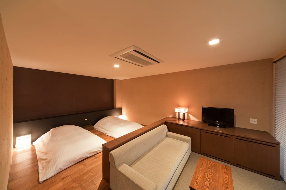 Habitación de hotel con dos camas, un sofá, un televisor y un escritorio.