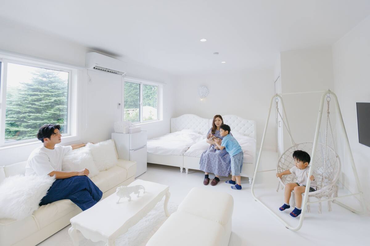 A modern, well-lit room with a sofa, a bed, a swing chair, and a TV.