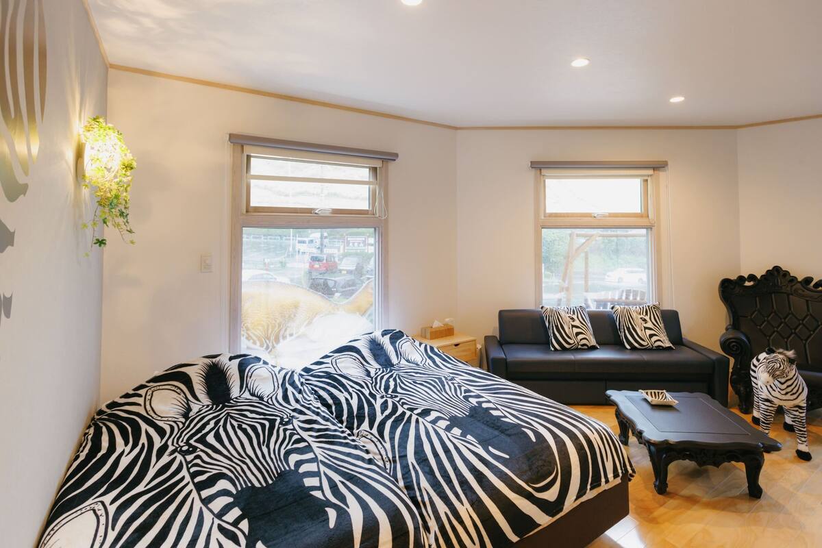 A modern living room with a zebra-patterned sofa, a small table, and a decorative wall piece.