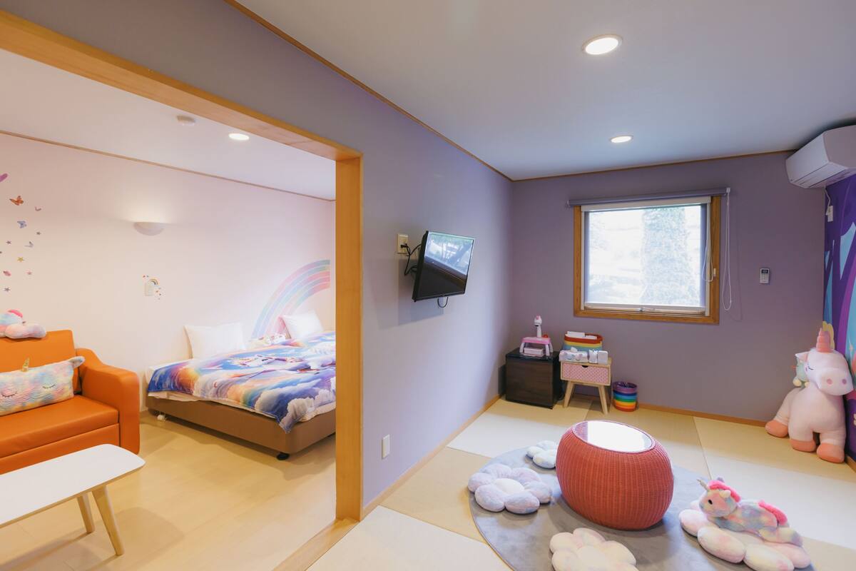 A child's bedroom with a bed, a sofa, a TV, and a window.