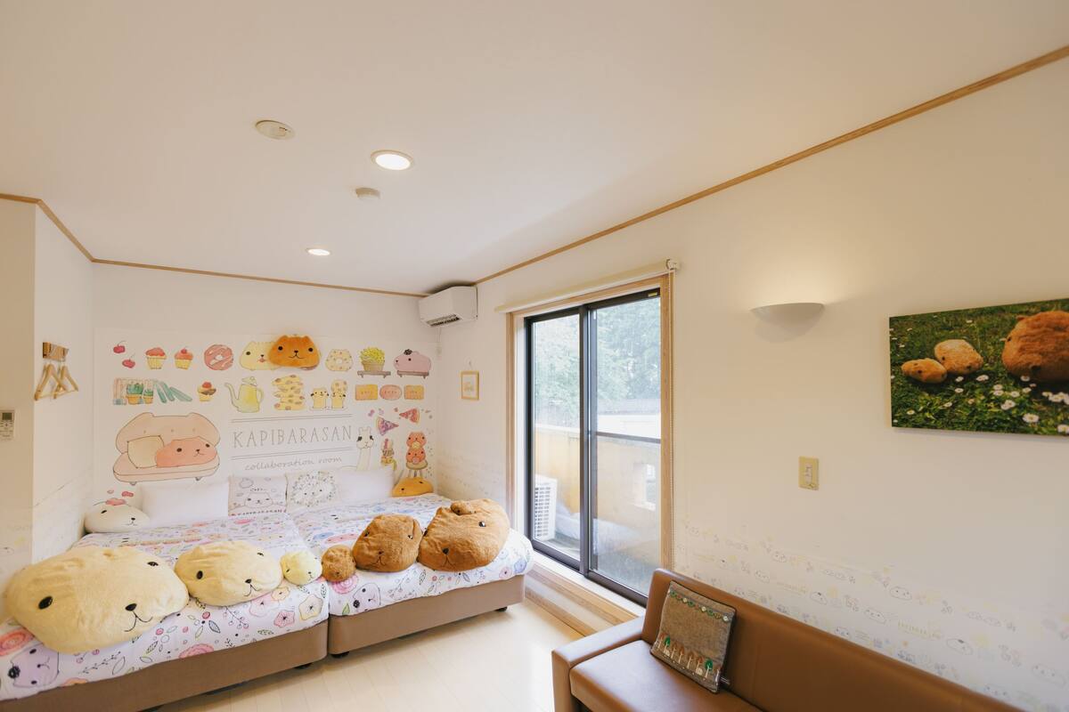 A cozy room with a bed, a window, and a wall decorated with children's drawings and teddy bears.