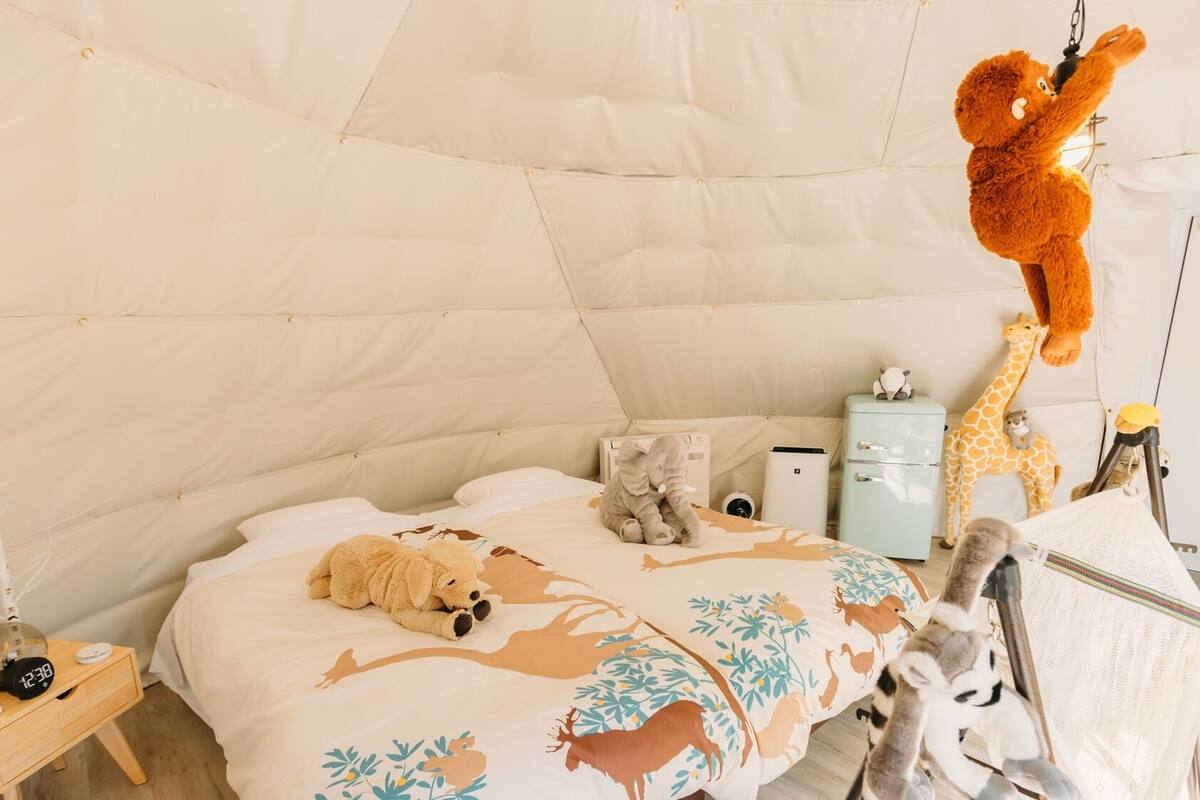 A cozy room with a bed, a nightstand, a teddy bear, and a giraffe plush toy.