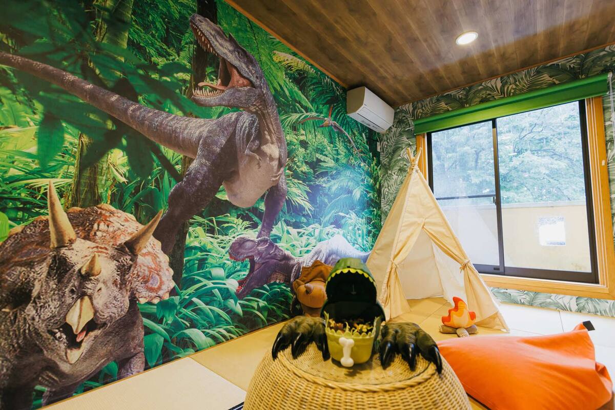 A room with a dinosaur mural, a tent, and a window with a view.