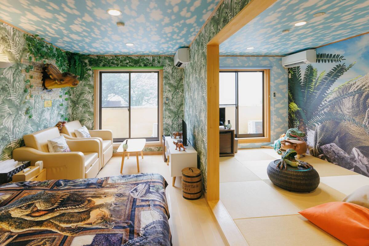 A room with a bed, sofa, and a dining area with a view.