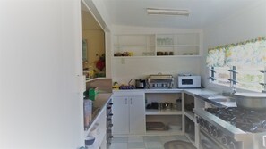 A compact kitchen with white cabinets, a gas stove, a microwave, and a toaster. - Kiikii Inn & Suites (Rarotonga)
