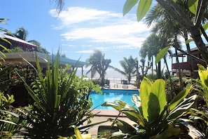 A pool surrounded by tropical plants and palm trees, with a clear sky above. - Kiikii Inn & Suites (Rarotonga)