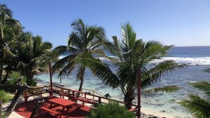 A beach with a wooden deck and benches, palm trees, and clear blue water. - Kiikii Inn & Suites (Rarotonga)