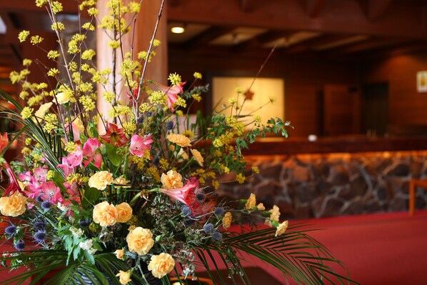 Un arreglo floral en una habitación con pared de piedra y techo de madera.