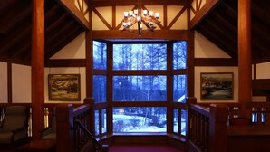 A room with a large window, wooden beams, a chandelier, and two framed pictures on the walls. - Tateshina Tokyu Hotel (Chino)