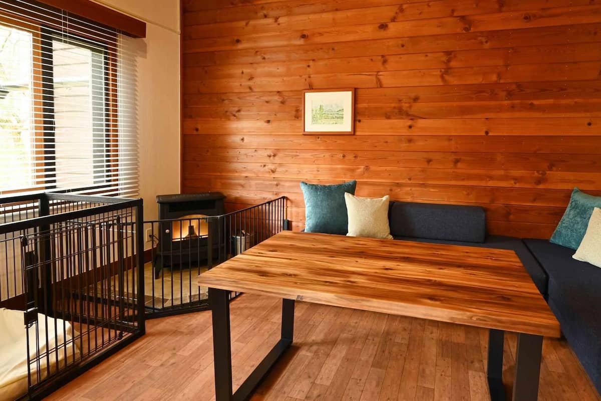 A wooden-paneled room with a sofa, a table, and a fireplace.
