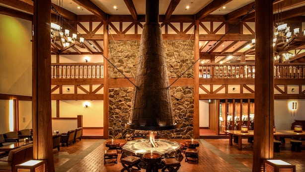 A lobby with a stone wall, wooden beams, and a central fire feature. - Tateshina Tokyu Hotel (Chino)