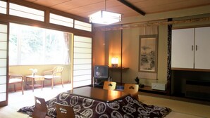Una habitación japonesa tradicional con suelo de tatami, una mesa baja y un televisor.