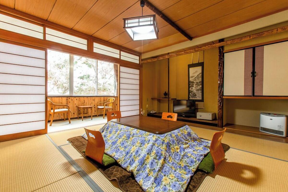 A traditional Japanese room with tatami flooring, a low table, and a futon bed.