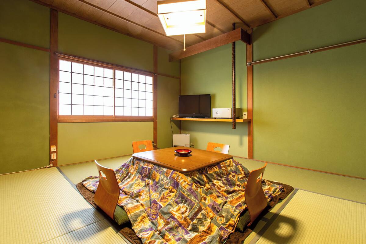 A traditional Japanese tatami room with a tatami mat floor, a low wooden table, and a shoji screen window.