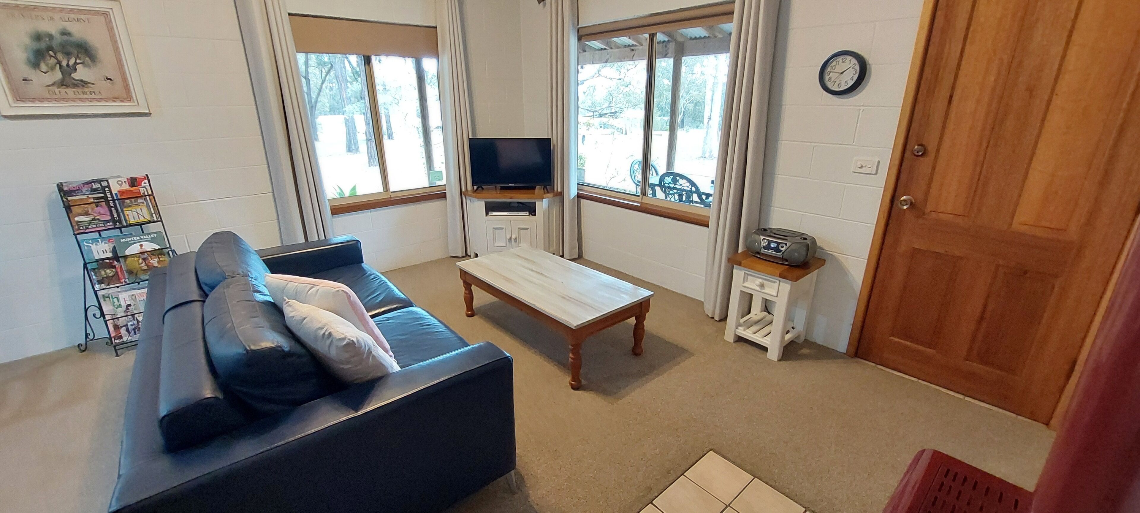 Uma sala de estar com sofá, mesa de centro, televisão e estante.