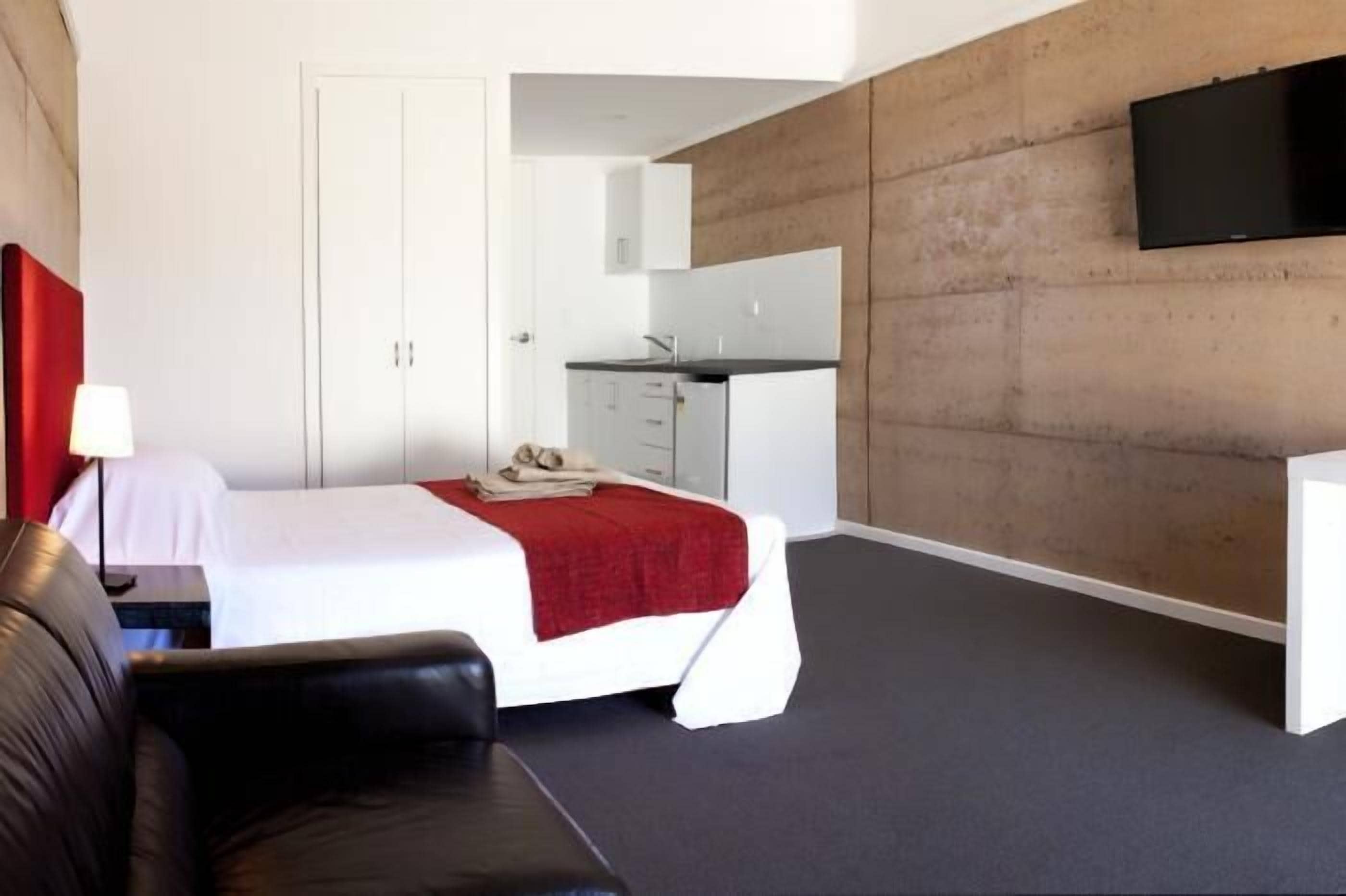 Une chambre d’hôtel moderne équipée d’un lit, d’un bureau, d’une chaise, d’une télévision et d’une armoire.