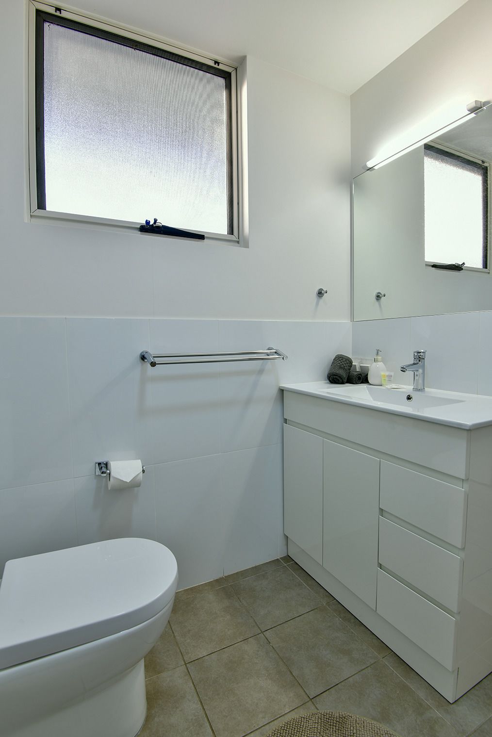 A bathroom with a toilet, a sink, and a mirror.