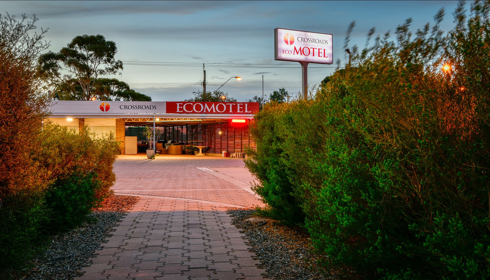 The entrance to the Crossroads Eco Motel with a paved pathway leading to the entrance.