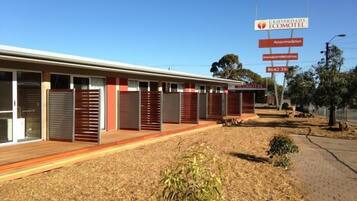 A motel with multiple rooms, a covered outdoor area, and a sign advertising accommodation.