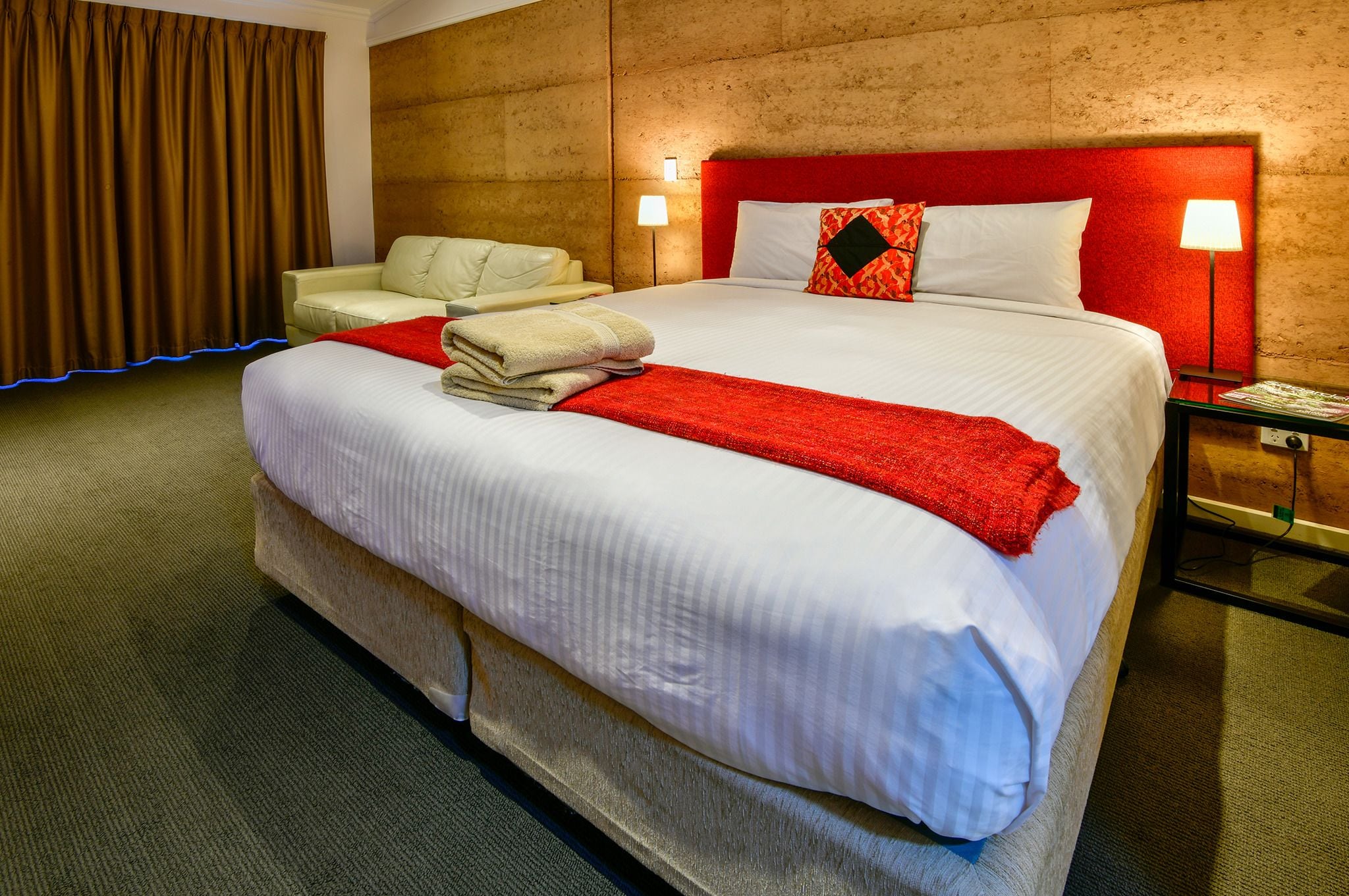 A hotel room with a large bed, a chair, a nightstand, and a lamp.