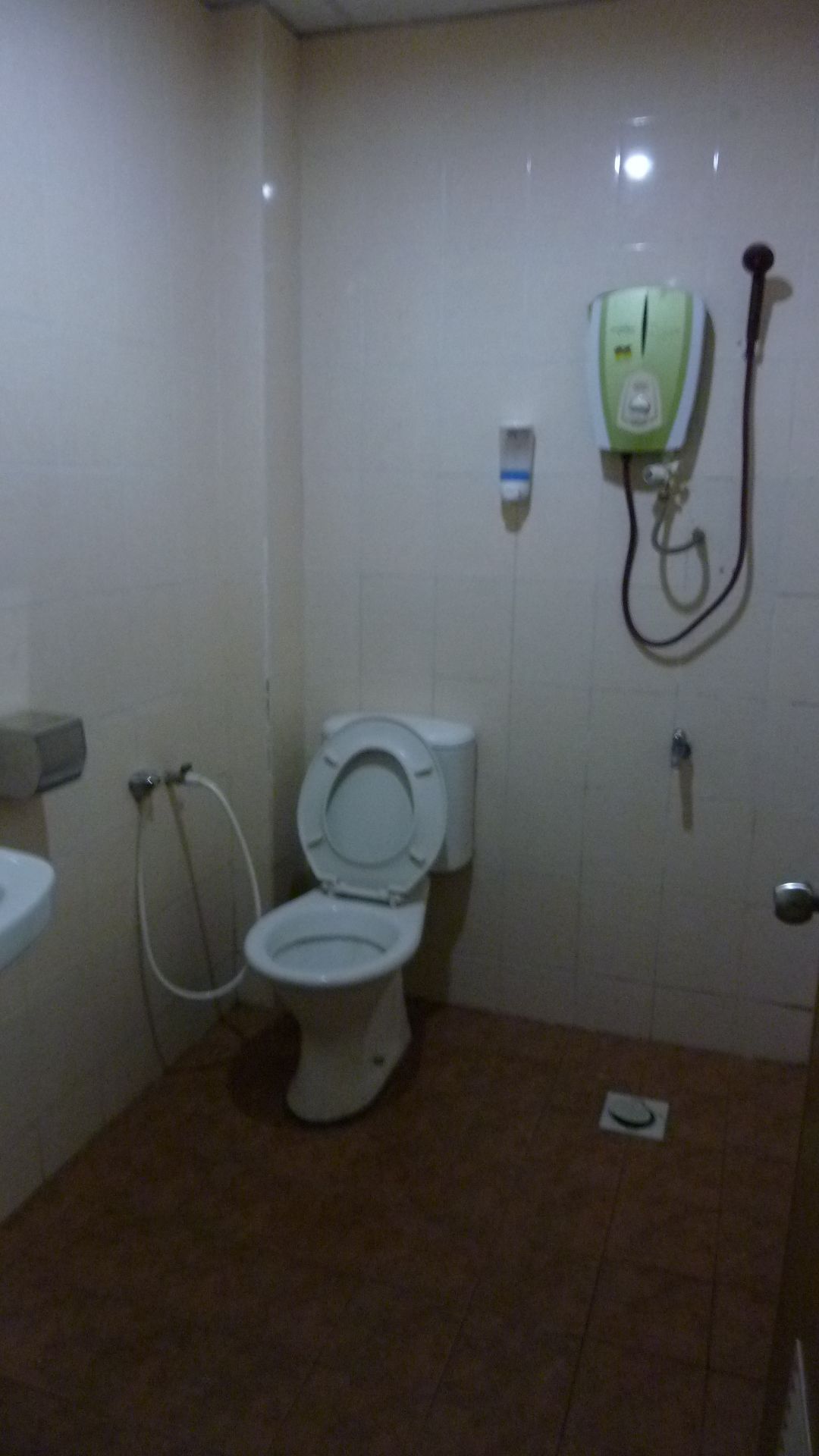 A small, tiled bathroom with a toilet, a sink, and a shower unit.