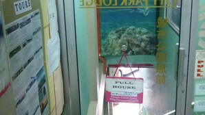 L’entrée d’un hôtel, avec une porte en verre, une enseigne au-dessus indiquant « SORTIE » et une affiche sur le mur faisant la publicité de « VISITES GUIDÉES ».