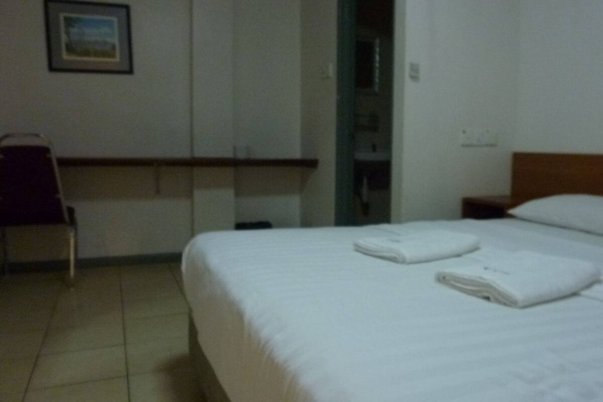 A hotel room with a bed, a chair, and a wardrobe.