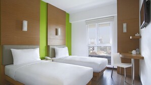 A hotel room with two beds, a desk, and a chair.