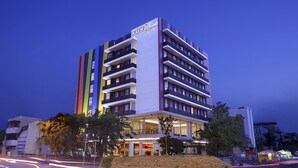 A multi-story hotel with a modern design, featuring balconies on each floor and a prominent entrance.