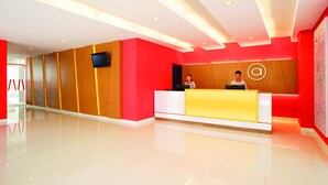 A modern reception area with a red and white color scheme, a reception desk, and a mounted television.