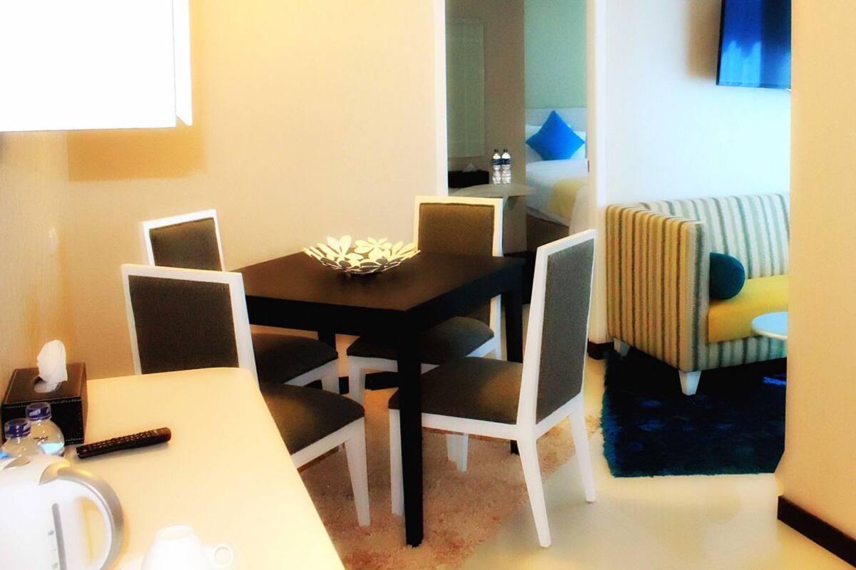 Une chambre d’hôtel compacte comprenant un coin repas, un canapé et une petite table avec un saladier.