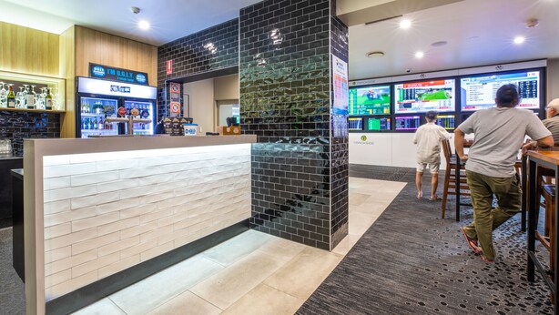 A modern bar area with a counter, a display of bottled beverages, and a seating area with tables and chairs. - Toongabbie Hotel (Toongabbie)