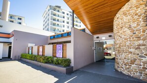 A modern hotel entrance with a stone facade, a wooden ceiling, and a sign for a bar and restaurant. - Toongabbie Hotel (Toongabbie)