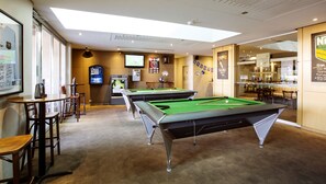 A pool table area with multiple tables and chairs, a bar area, and a television screen. - Toongabbie Hotel (Toongabbie)