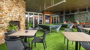 An outdoor area with a pool table, green artificial turf, stone wall, and outdoor seating. - Toongabbie Hotel (Toongabbie)