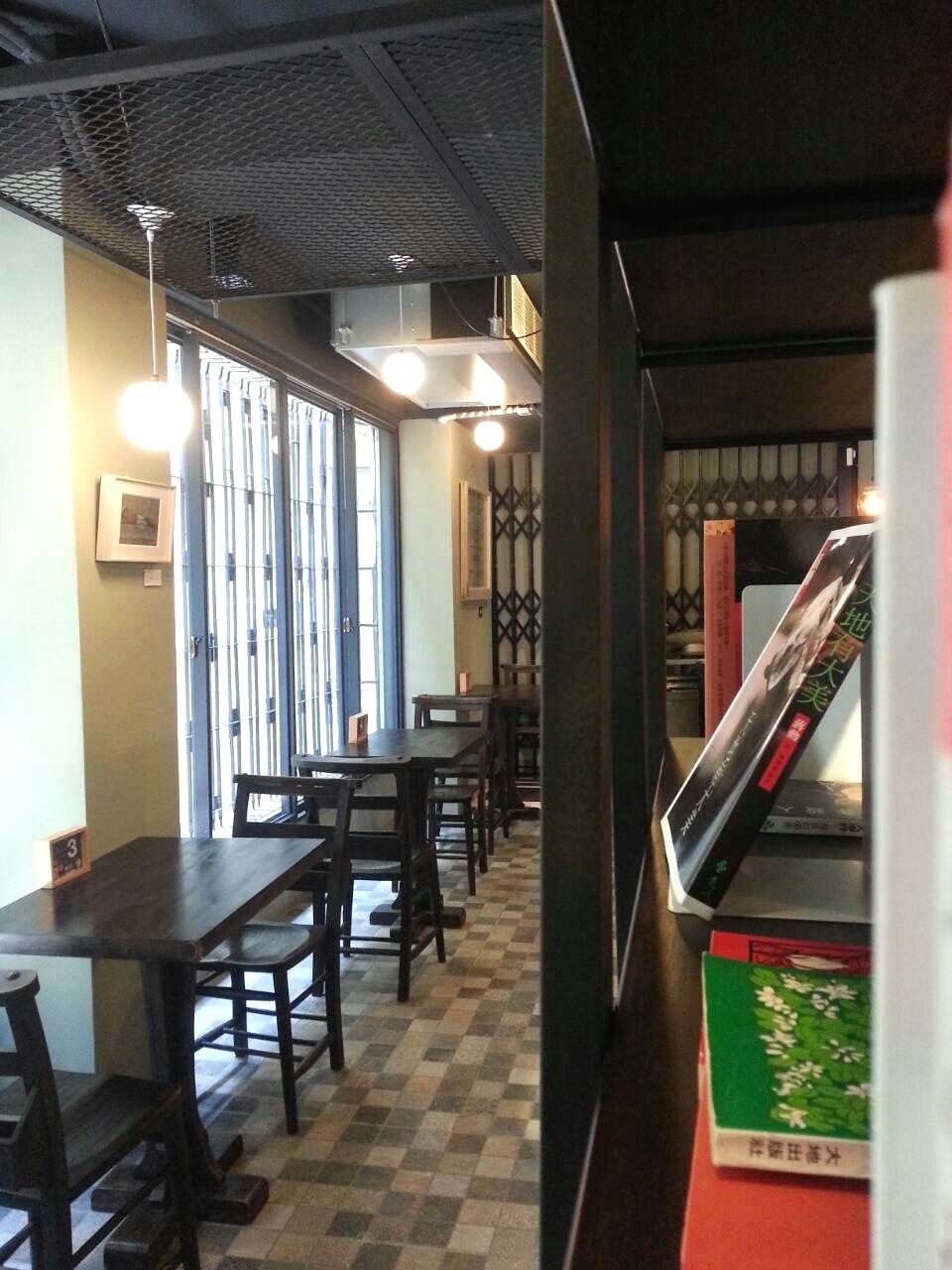 A restaurant interior with wooden tables and chairs, a checkered floor, and a menu stand with books.