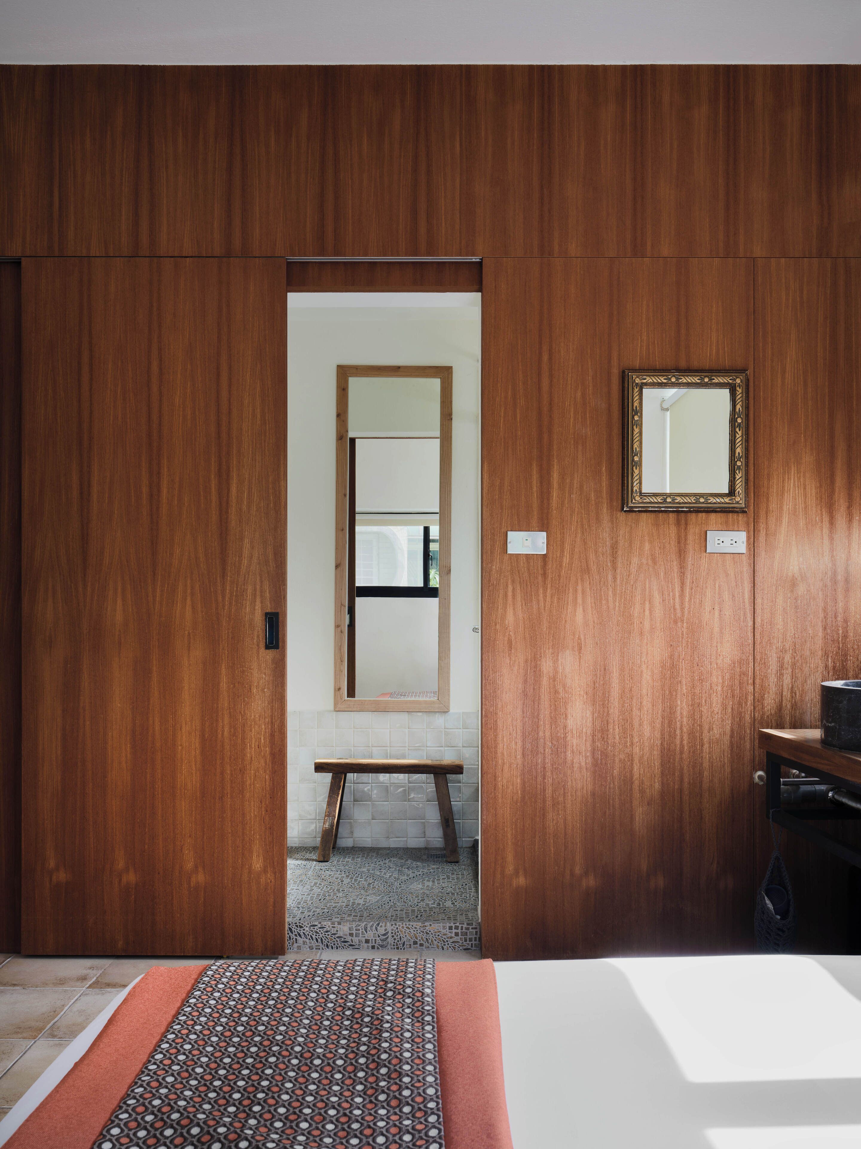 Hotelkamer met een houten garderobe, een spiegel, een nachtkastje en een kamerbreed tapijt met dessin.