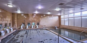 Una amplia piscina interior con múltiples duchas y suelo de baldosas.