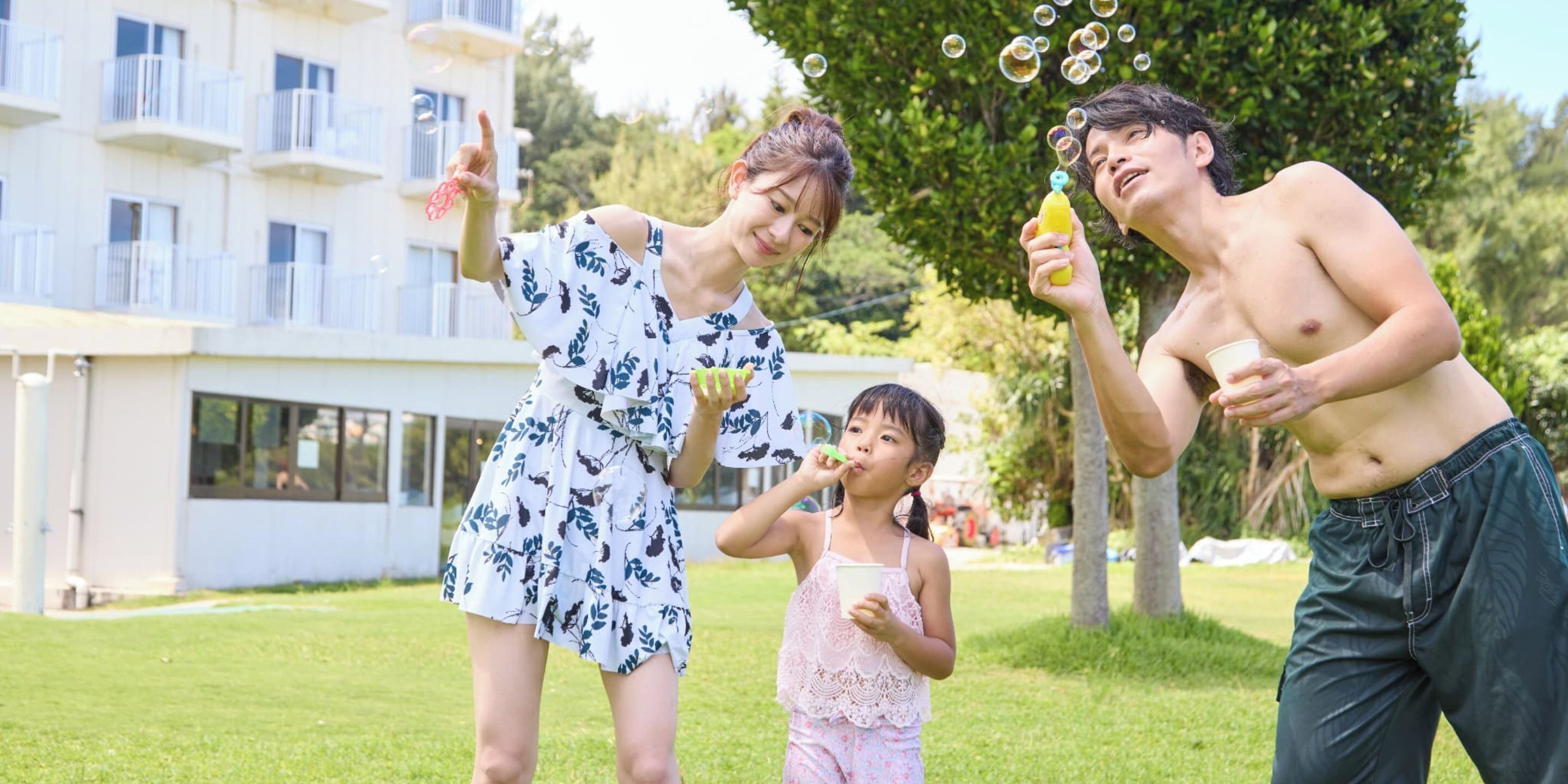 A family of three in a park with a building in the background.