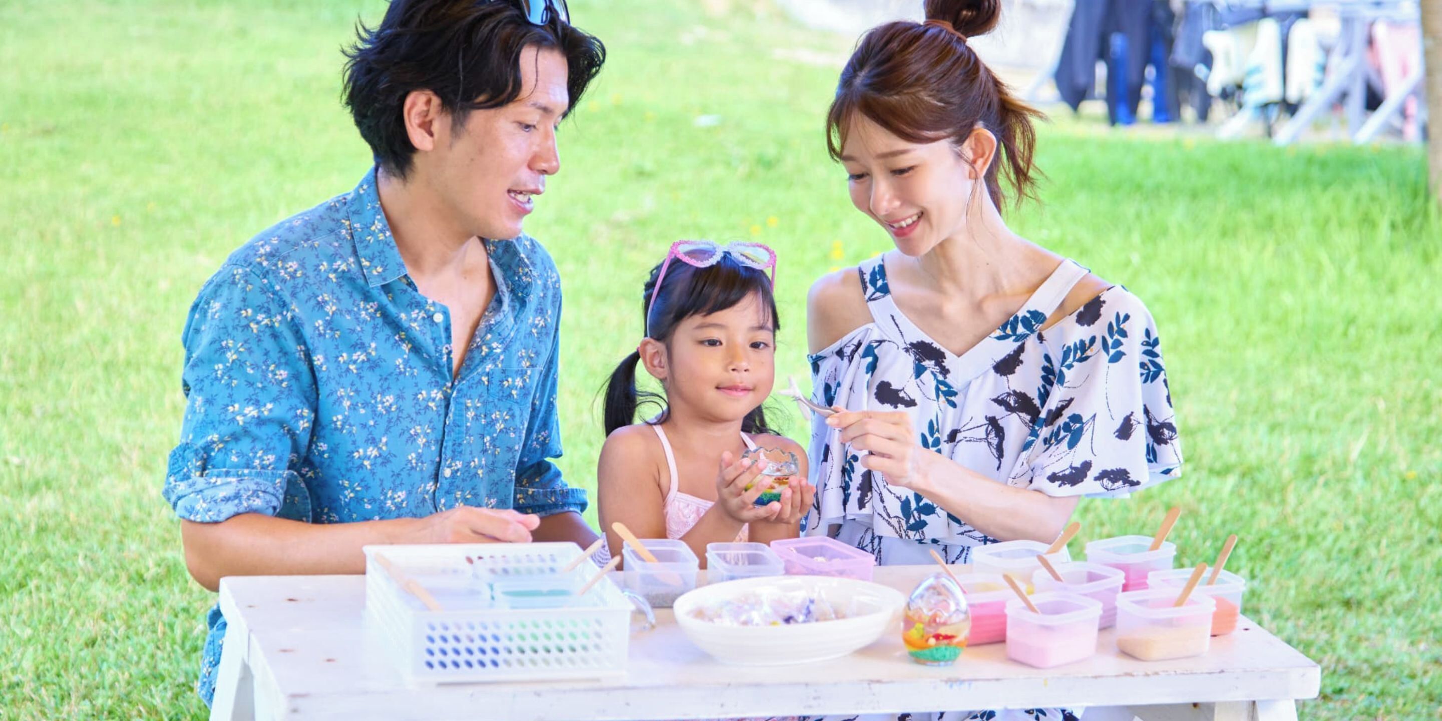 A family at an outdoor event with a table set up with various items.