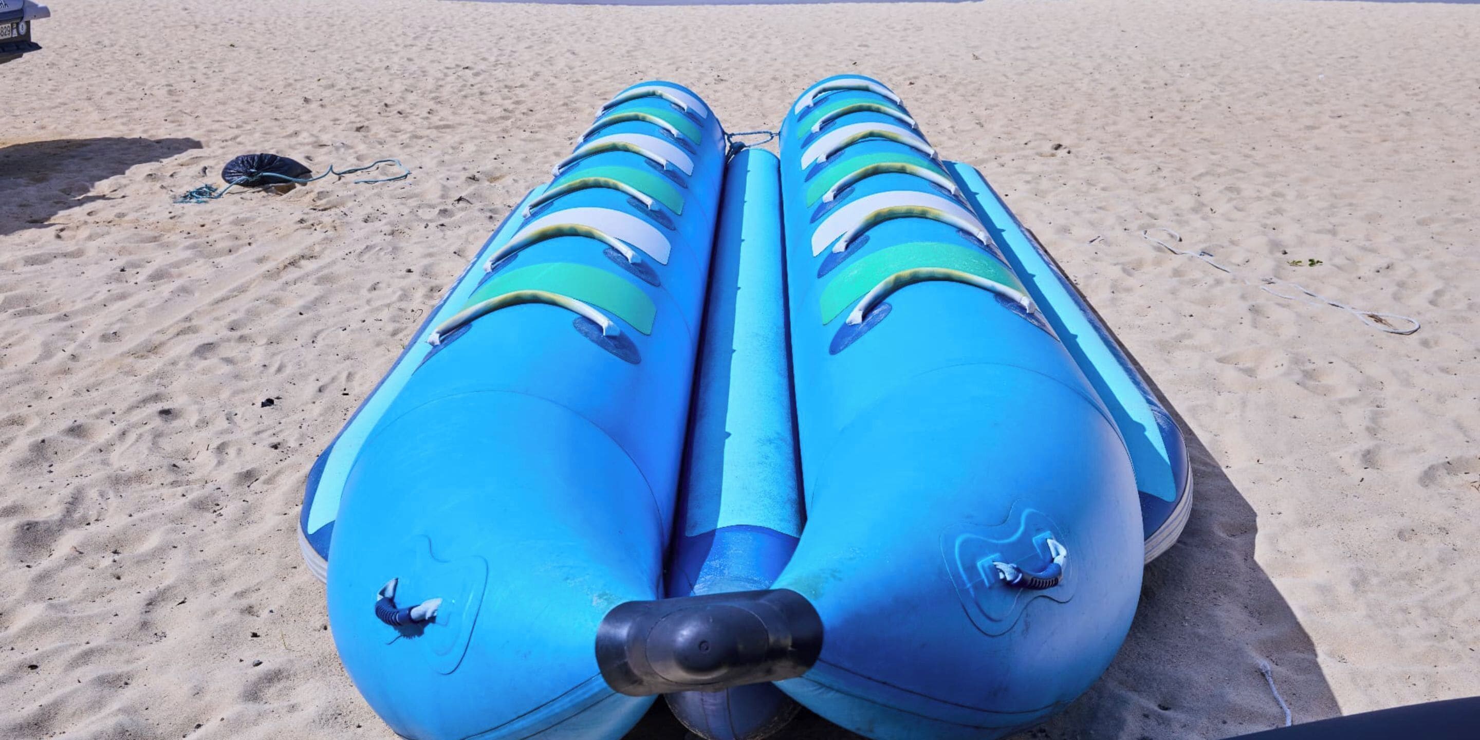 A blue inflatable raft on a sandy beach.