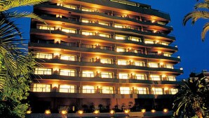 A multi-story hotel with balconies, a ground-level entrance, and a pool area. - Hotel Harvest Ito (Ito)