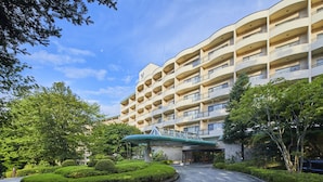 Un hôtel à plusieurs étages, doté d’une façade incurvée, d’une entrée couverte et d’une allée bordée de verdure.